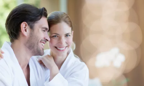 Portrait happy young couple in bathrobes hugging in spa